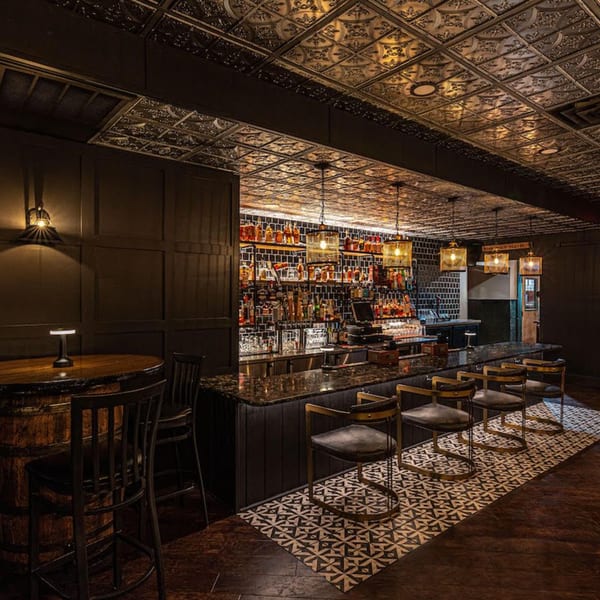The Barrel Room at Beckett’s bar with dark wood, patterned ceiling, and bottles on shelves.