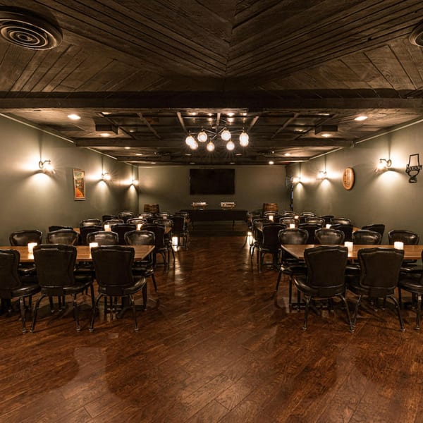 The Barrel Room at Beckett's, a dimly lit private dining room with dark wood floors and tables.