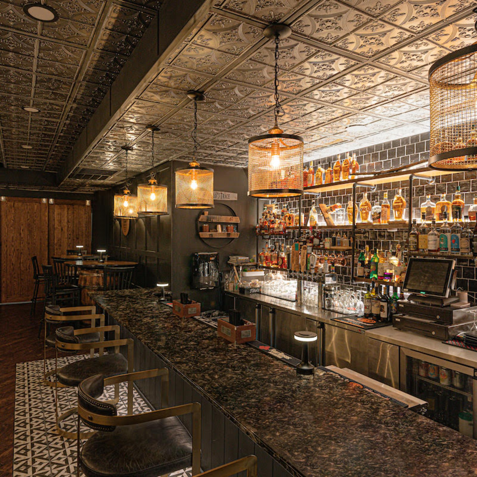 The Barrel Room at Beckett’s bar with a dark granite counter, bar stools, and liquor bottles on shelves.