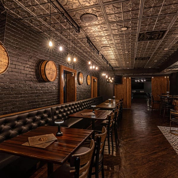 The Barrel Room at Beckett's, a dimly lit American restaurant with dark brick walls, leather booths, and wooden tables.